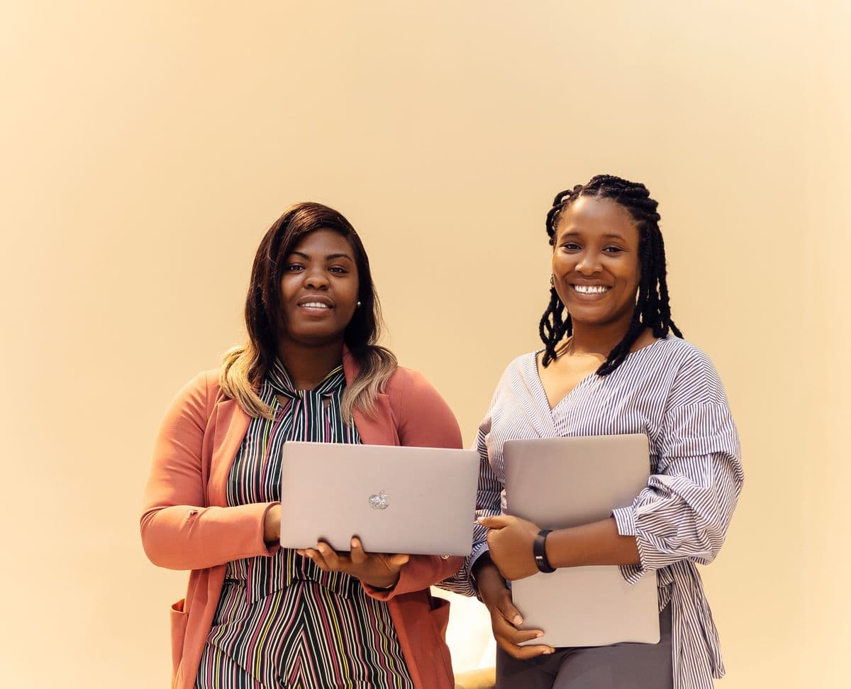 Two colleagues holding laptops, ready to demo a product