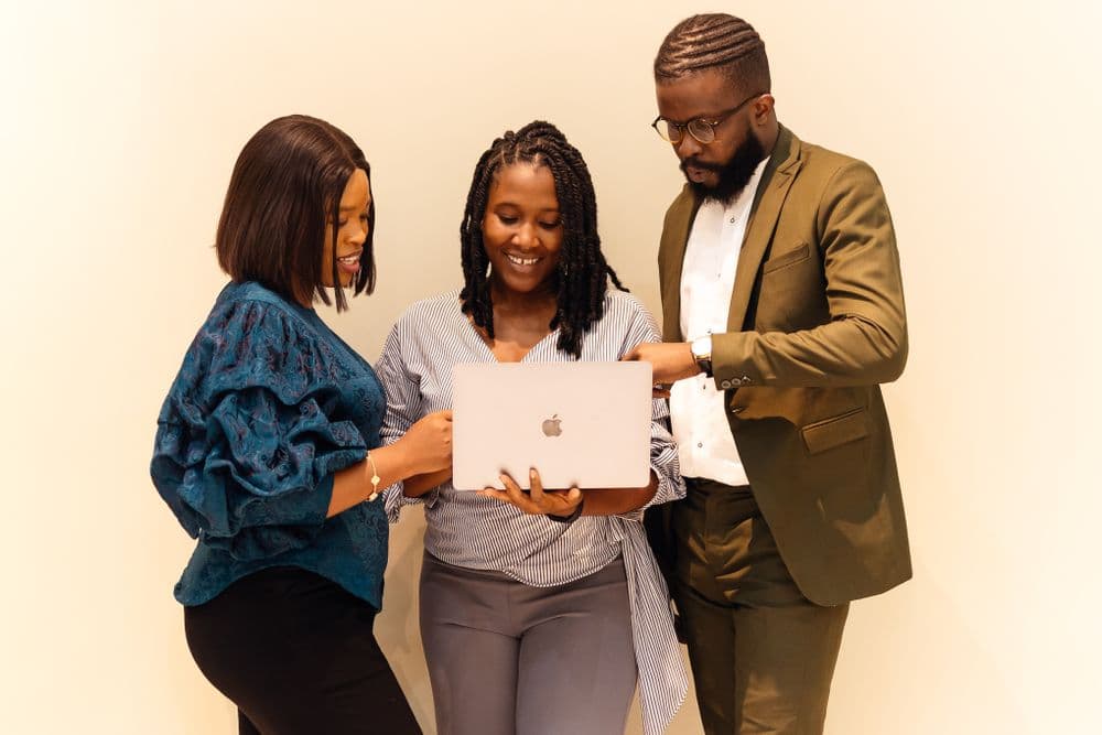 Three colleagues reviewing a product on a laptop